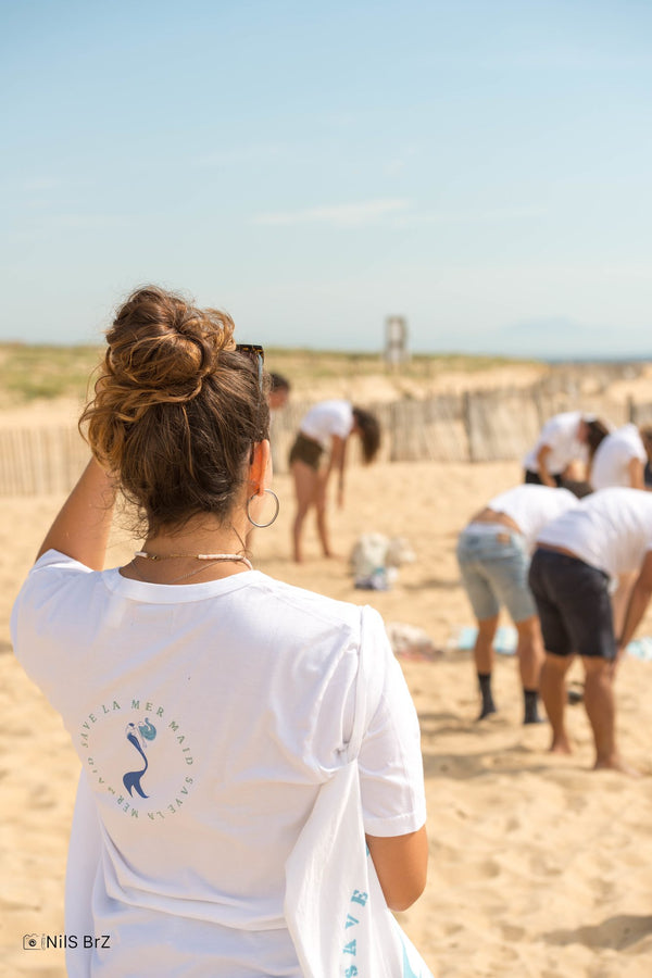 Freiwillige von Save La Mermaid von hinten am Strand