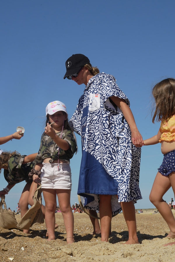 Maud Le Car im Save La Mermaid-Poncho mit Kindern in den Dünen