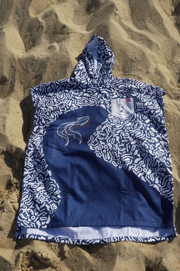 Der Poncho Save La Mermaid liegt ausgebreitet im Sand